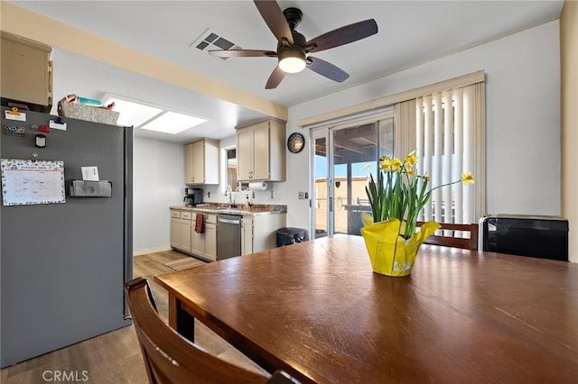 kitchen featuring stainless steel appliances, light hardwood / wood-style floors, sink, cream cabinets, and ceiling fan