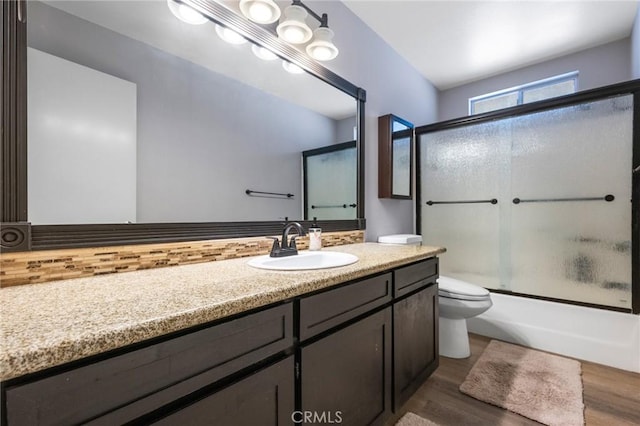 full bathroom featuring toilet, vanity, wood-type flooring, and shower / bath combination with glass door