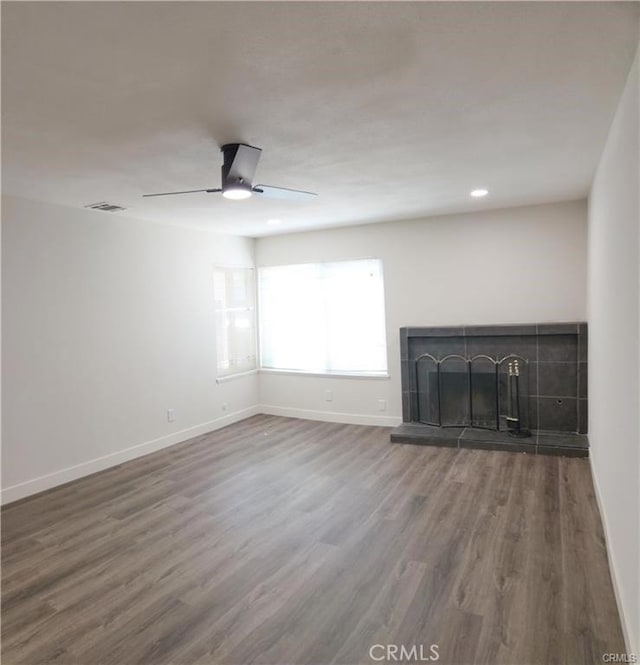 unfurnished living room featuring ceiling fan, wood-type flooring, and a fireplace