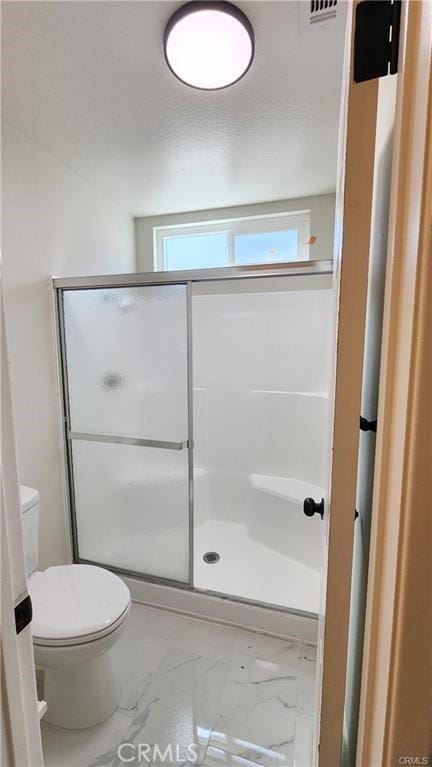 bathroom featuring toilet and a shower with door