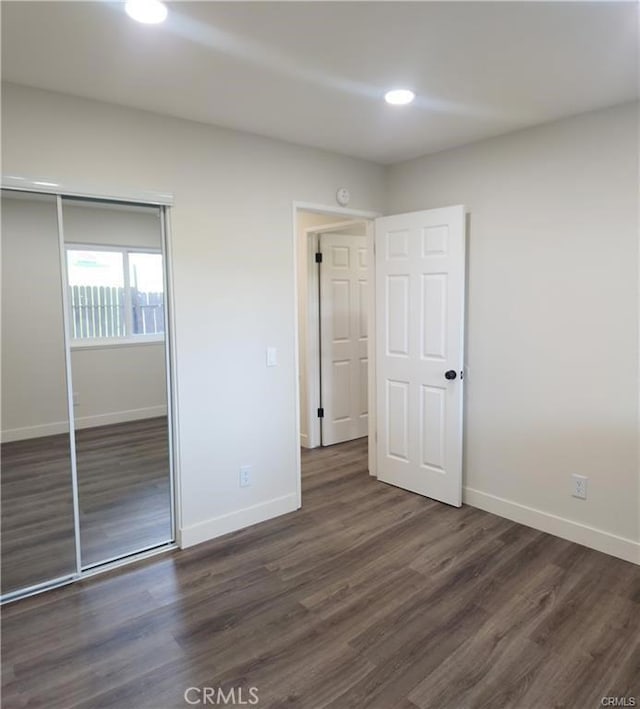 unfurnished bedroom with dark wood-type flooring and a closet