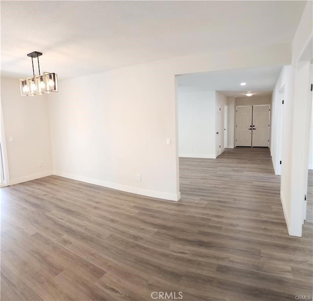 spare room featuring dark wood-type flooring and a notable chandelier