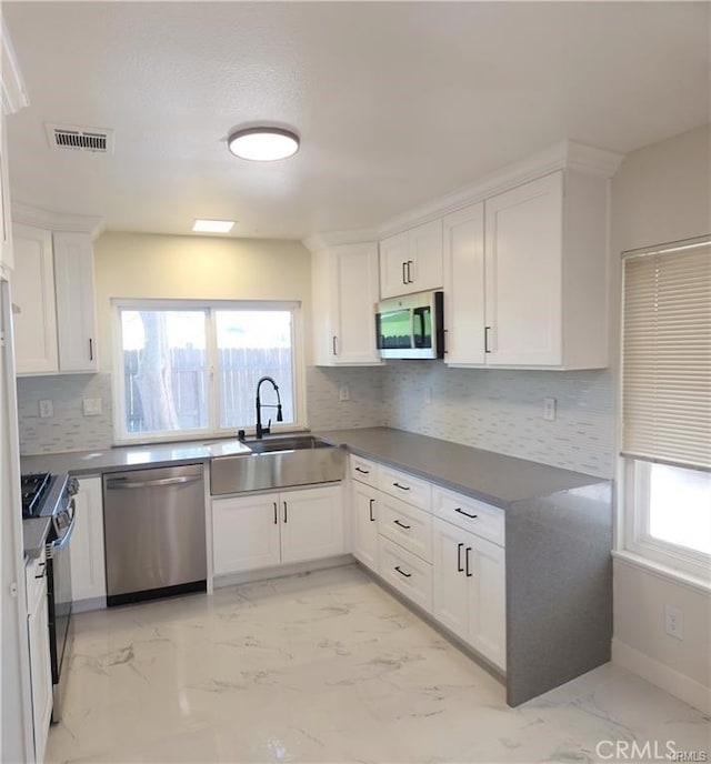 kitchen with backsplash, sink, white cabinetry, and appliances with stainless steel finishes