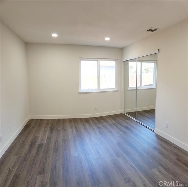 empty room with dark hardwood / wood-style flooring and plenty of natural light