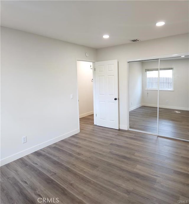 unfurnished bedroom with a closet and dark wood-type flooring