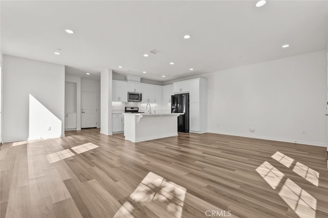 unfurnished living room featuring light hardwood / wood-style floors and sink