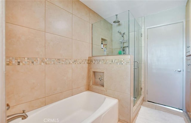 bathroom with tile walls and independent shower and bath