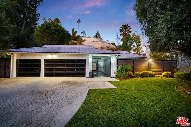 ranch-style home with a garage and a lawn