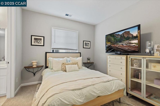 bedroom featuring light colored carpet and ensuite bathroom