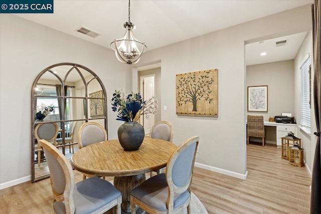 dining space with a wealth of natural light, an inviting chandelier, and light hardwood / wood-style flooring