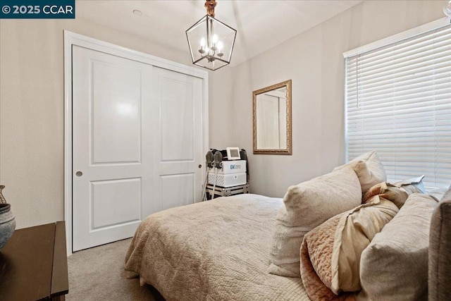 carpeted bedroom featuring a closet and a chandelier