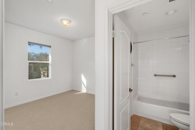 bathroom with toilet and tiled shower / bath combo