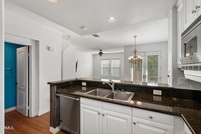 kitchen with stainless steel appliances, white cabinets, decorative light fixtures, and sink