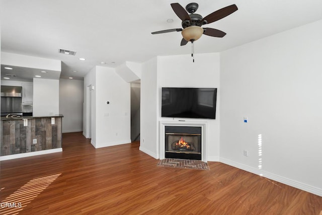 unfurnished living room featuring ceiling fan and dark hardwood / wood-style floors