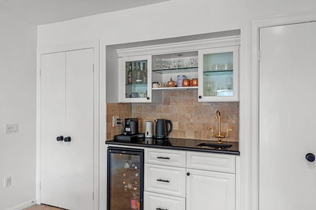 bar with wine cooler, sink, white cabinetry, and tasteful backsplash