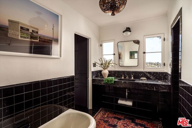 bathroom with vanity, tile walls, and a tub