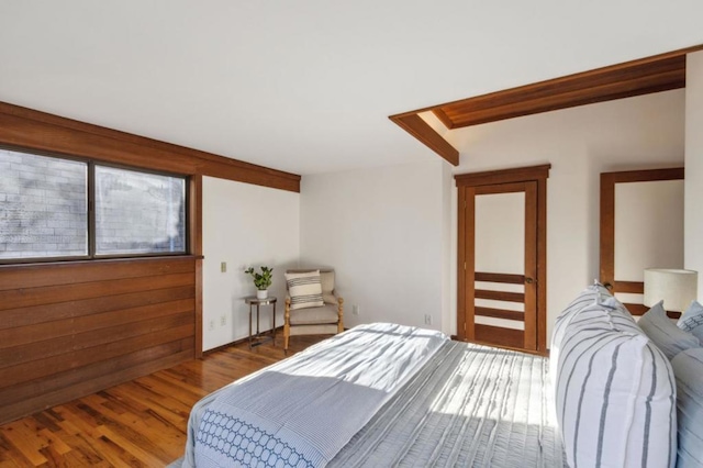 bedroom with hardwood / wood-style floors and wooden walls