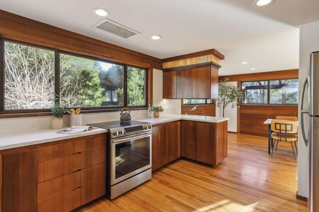 kitchen featuring light wood-type flooring, kitchen peninsula, appliances with stainless steel finishes, and a wealth of natural light