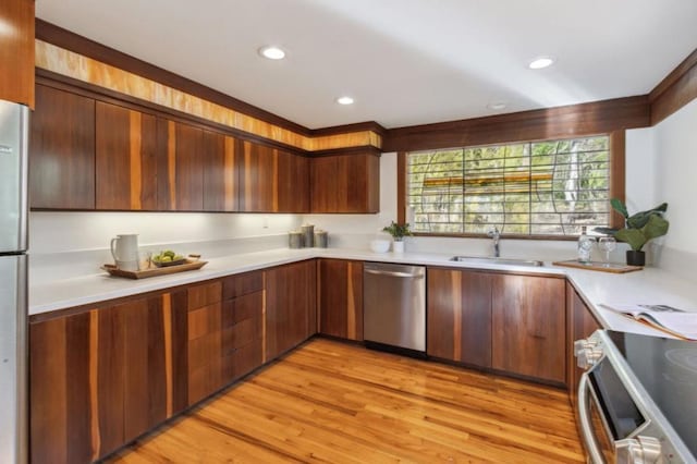 kitchen featuring sink, crown molding, light hardwood / wood-style flooring, and stainless steel appliances