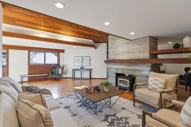 living room featuring light hardwood / wood-style floors, a wood stove, and beamed ceiling