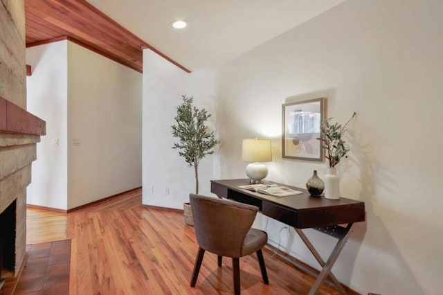 home office featuring a tiled fireplace and light hardwood / wood-style floors