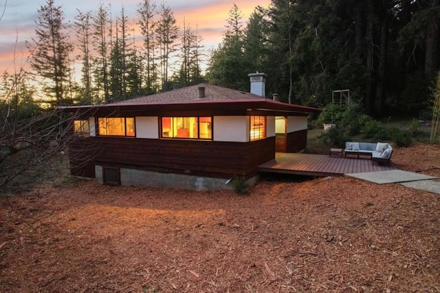 back house at dusk featuring a deck and outdoor lounge area