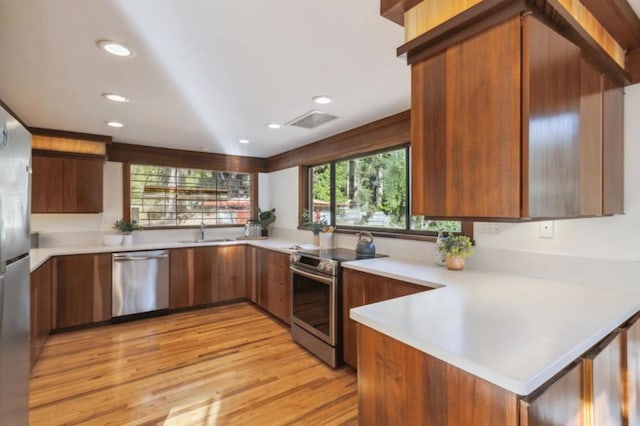 kitchen featuring light wood-type flooring, appliances with stainless steel finishes, kitchen peninsula, and sink