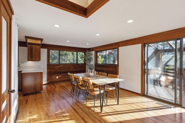 dining space featuring plenty of natural light, light hardwood / wood-style flooring, and wooden walls