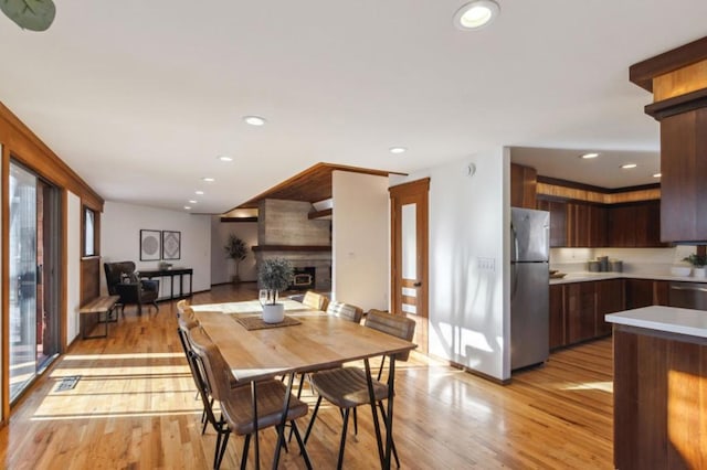 dining space with light hardwood / wood-style floors and a large fireplace