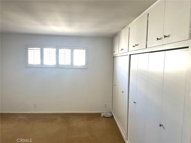 unfurnished bedroom featuring light carpet, baseboards, and a closet