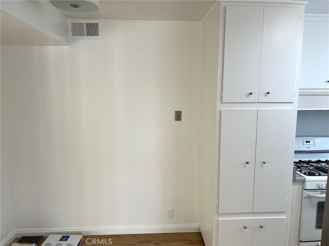 kitchen with white cabinetry, white gas stove, baseboards, and visible vents