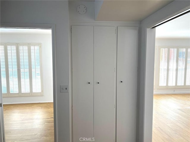 hall with baseboards and light wood-style floors