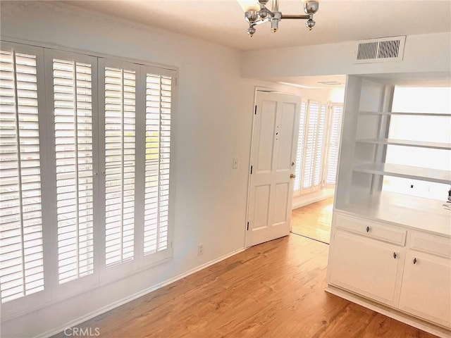 interior space with visible vents, light wood-style flooring, and baseboards