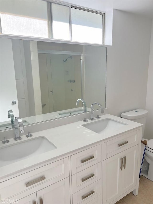 bathroom with double vanity, a shower stall, toilet, and a sink