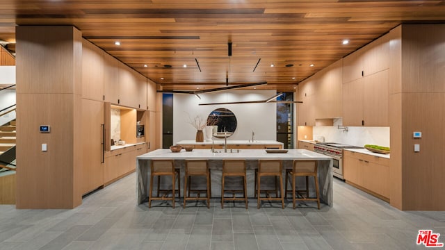 kitchen featuring light brown cabinetry, wood ceiling, a breakfast bar, and range with two ovens