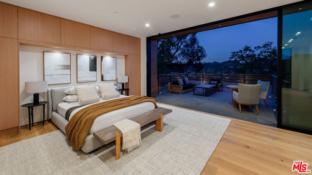 bedroom with floor to ceiling windows and light hardwood / wood-style floors