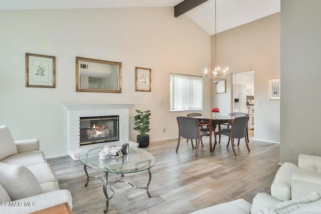 living room with a fireplace, hardwood / wood-style floors, an inviting chandelier, and beamed ceiling