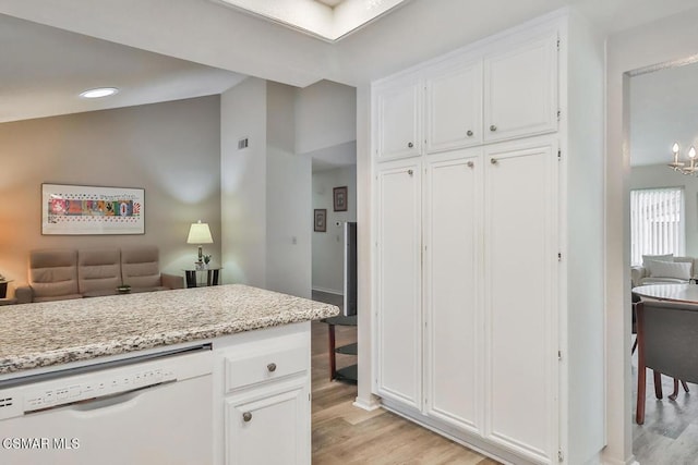 kitchen with light hardwood / wood-style flooring, dishwasher, white cabinets, light stone countertops, and a notable chandelier