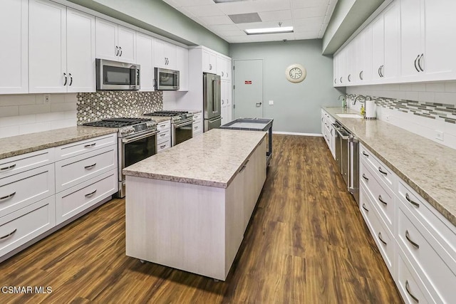 kitchen featuring a kitchen island, a paneled ceiling, high end appliances, and white cabinetry