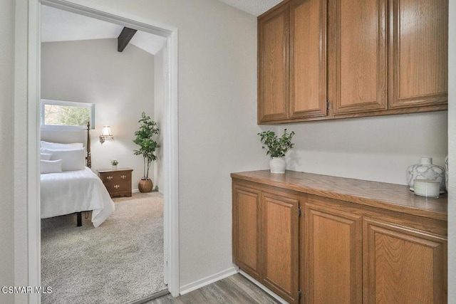 hall with light carpet and lofted ceiling with beams