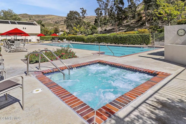 view of swimming pool with a mountain view, a patio area, and a hot tub