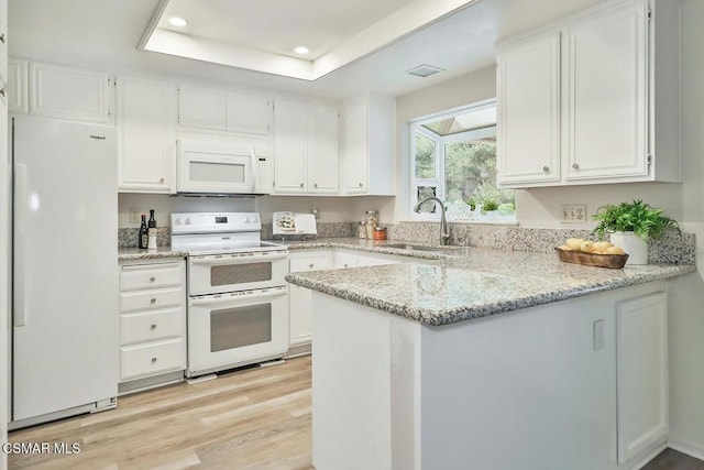 kitchen featuring white appliances, white cabinets, sink, kitchen peninsula, and a tray ceiling