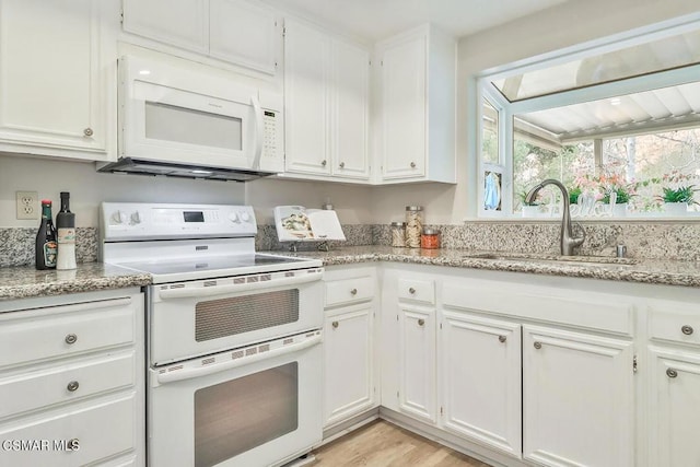 kitchen with white appliances, white cabinetry, light hardwood / wood-style floors, sink, and light stone counters