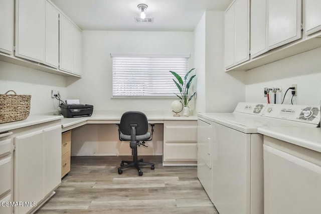 clothes washing area with cabinets, washer and clothes dryer, and light hardwood / wood-style floors