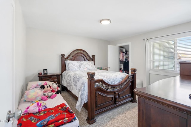 bedroom with light colored carpet, a closet, and a spacious closet