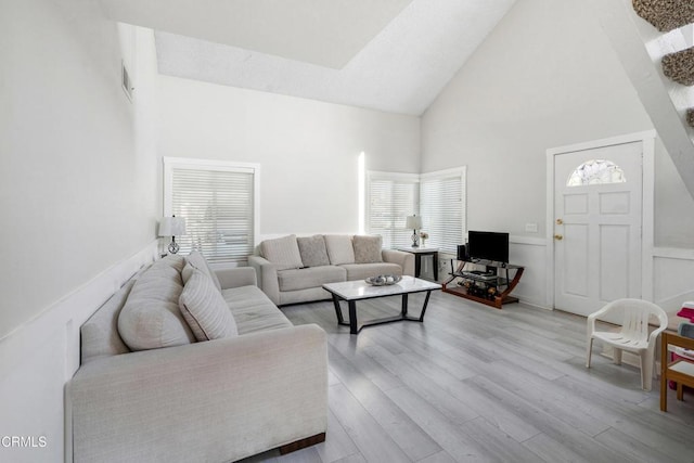 living room with high vaulted ceiling and wood finished floors