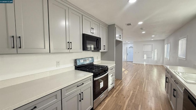 kitchen featuring black appliances, light wood-type flooring, and gray cabinets