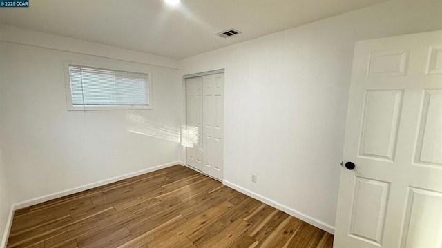 unfurnished bedroom featuring a closet and dark wood-type flooring