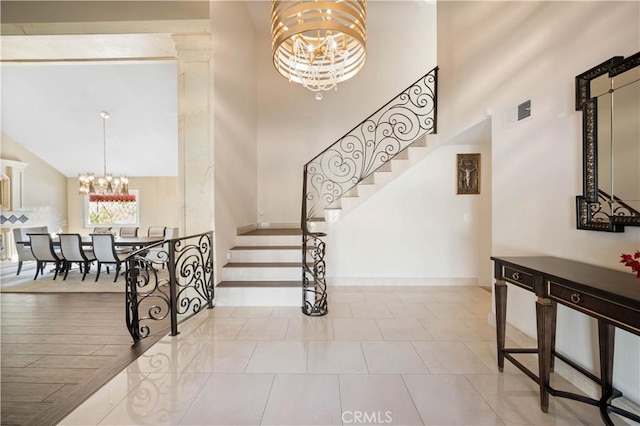 stairs with a high ceiling, a chandelier, and tile patterned flooring