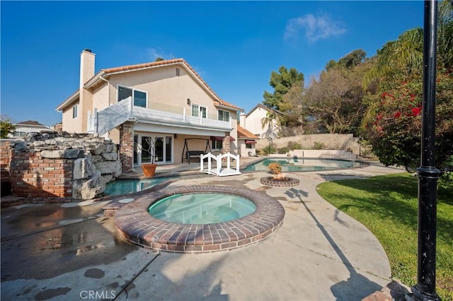 rear view of property featuring a balcony, a patio area, and a pool with hot tub